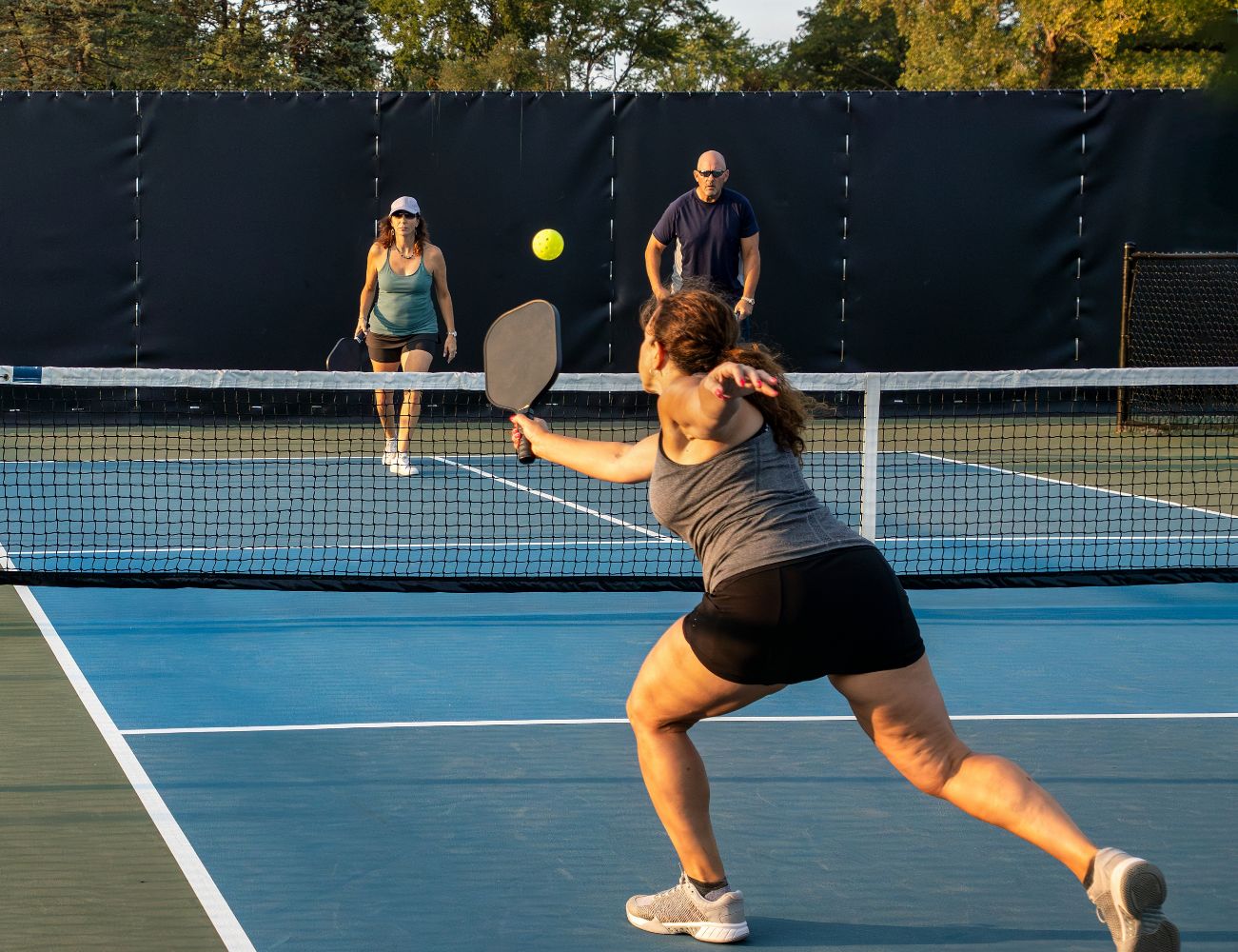 Uma mulher jogando Pickleball em uma quadra aberta